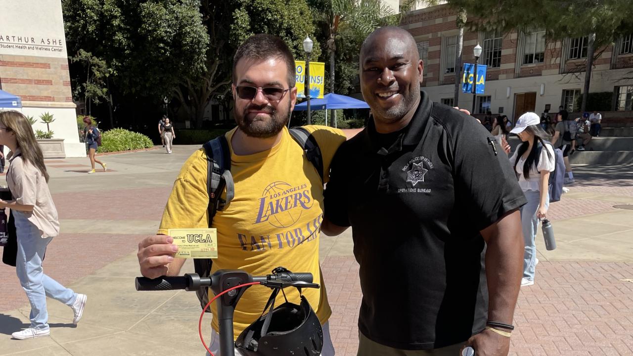 Officer London McBride rewards a student with a meal voucher for walking his scooter